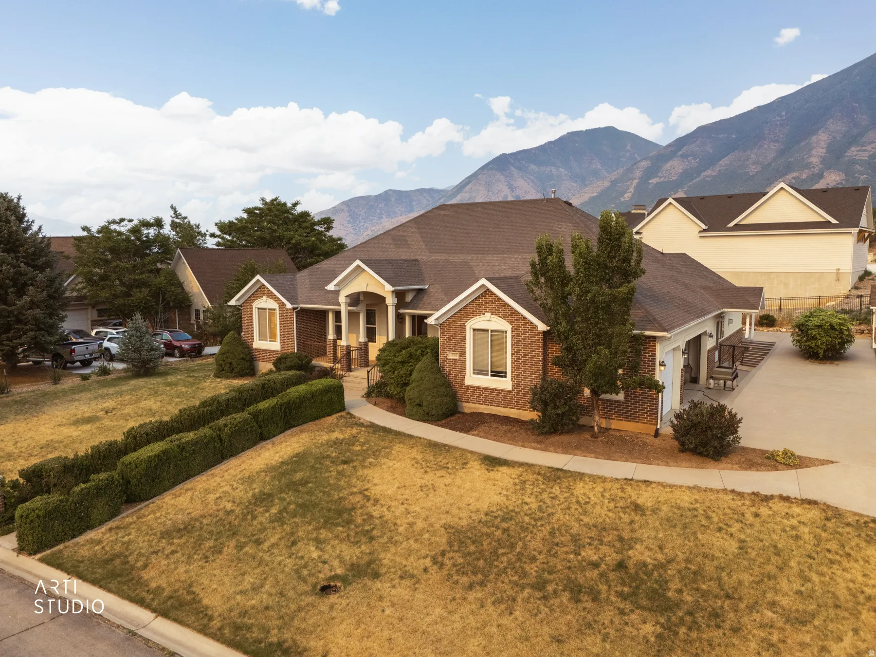 Brick exterior residence featuring a front porch with columns, a multi-car driveway, and an attached two-car garage