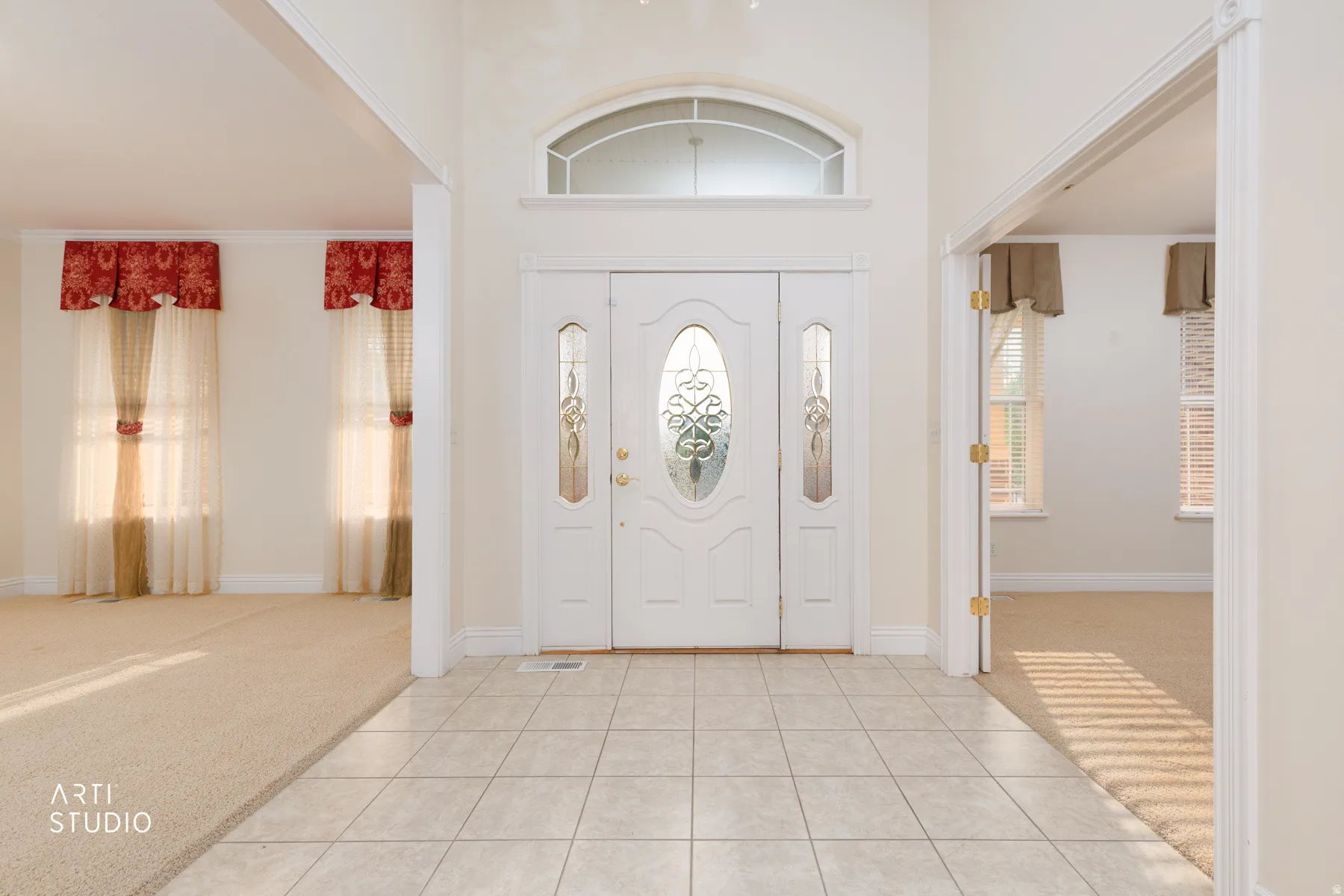 Entryway featuring a decorative front door with side lites and transom window, tile flooring, and arched doorways leading to carpeted interior spaces
