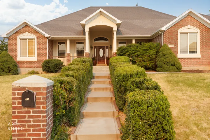 Brick exterior with covered front porch, featuring a dark wood entry door with an arched transom