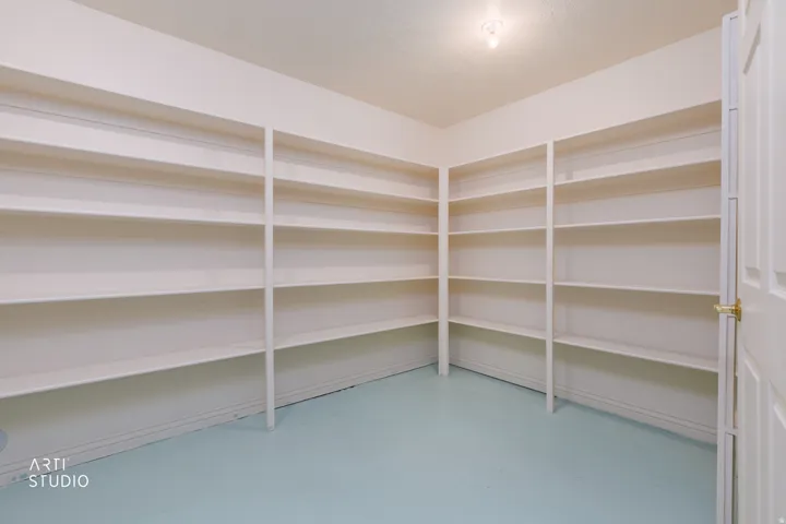 Expansive storage room featuring floor-to-ceiling built-in shelving, light blue flooring, and a flush mount ceiling light