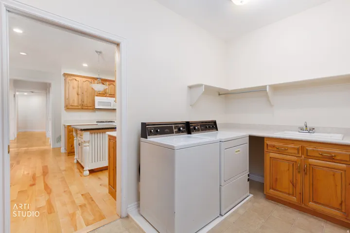 Dedicated laundry area featuring a utility sink, light wood cabinetry, and integrated shelving