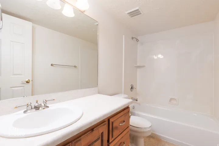 Bathroom featuring a single vanity with an integrated sink, a white countertop, and a wood-finish cabinet with drawer storage
