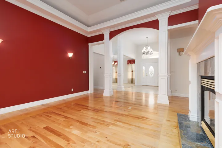 Open concept living space featuring light wood-finish flooring, a tray ceiling, and a fireplace with a stone surround