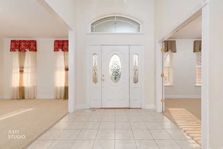 Entryway featuring a decorative front door with side lites and transom window, tile flooring, and arched doorways leading to carpeted interior spaces