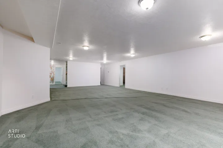 Spacious room with plush green carpeting, recessed lighting, and crisp white walls