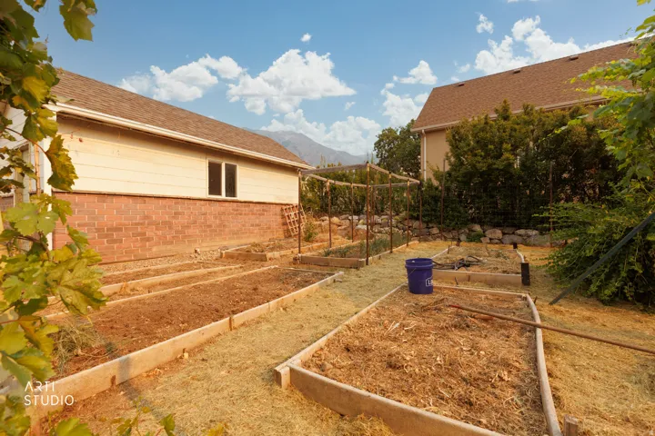 Terraced garden beds featuring established trellises, mulched and tilled soil, and a stone retaining wall
