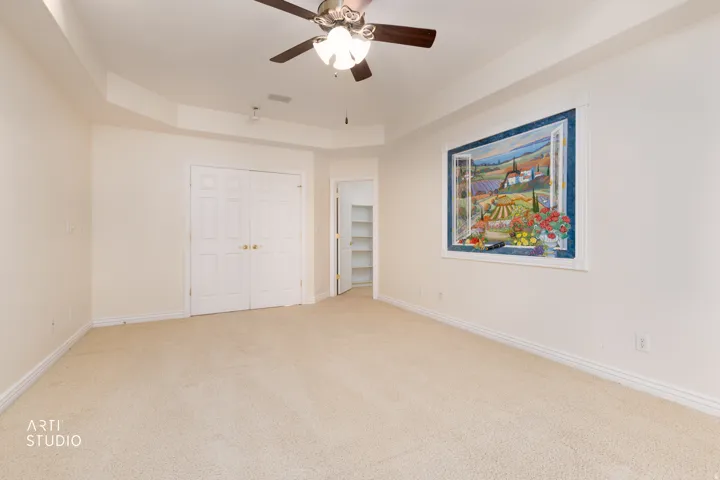 Spacious master bedroom with plush carpet flooring and a ceiling fan