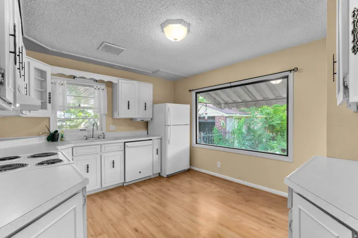 Kitchen featuring wood-finish flooring, white cabinetry, a white refrigerator, and a built-in electric range with an oven