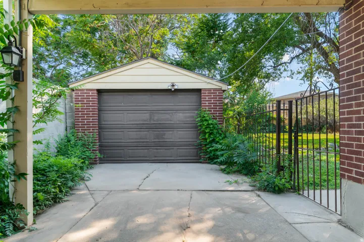 Detached garage featuring brick and siding construction, a panel garage door, and an exterior light fixture