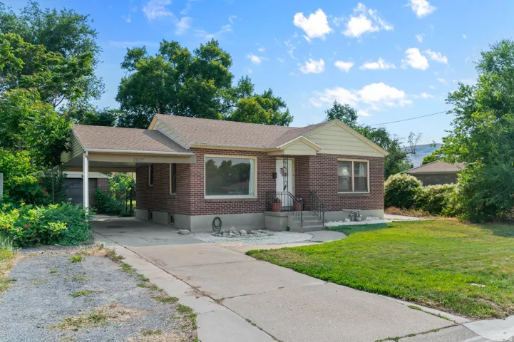 Brick exterior home featuring a covered carport, pitched roof, and a concrete driveway