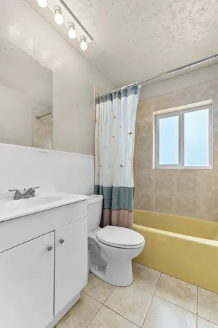 Bathroom featuring a single vanity with a white countertop and cabinet storage, track lighting, and a window for natural light