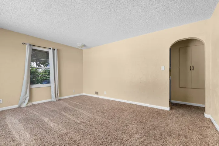 Carpeted interior space with a single window and an arched doorway
