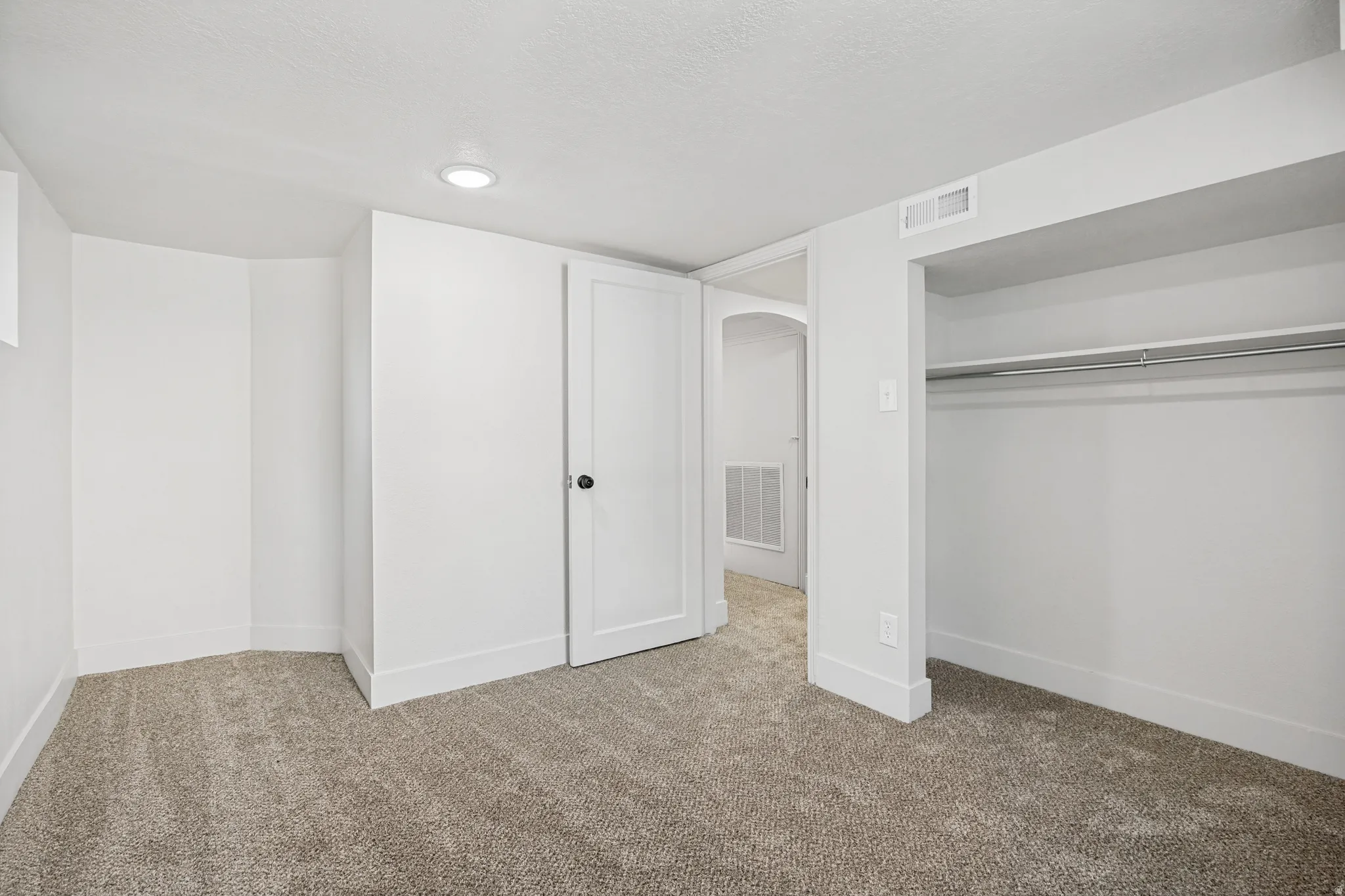 Carpeted room featuring white walls, recessed ceiling lighting, a built-in closet with hanging rod, and white trim throughout