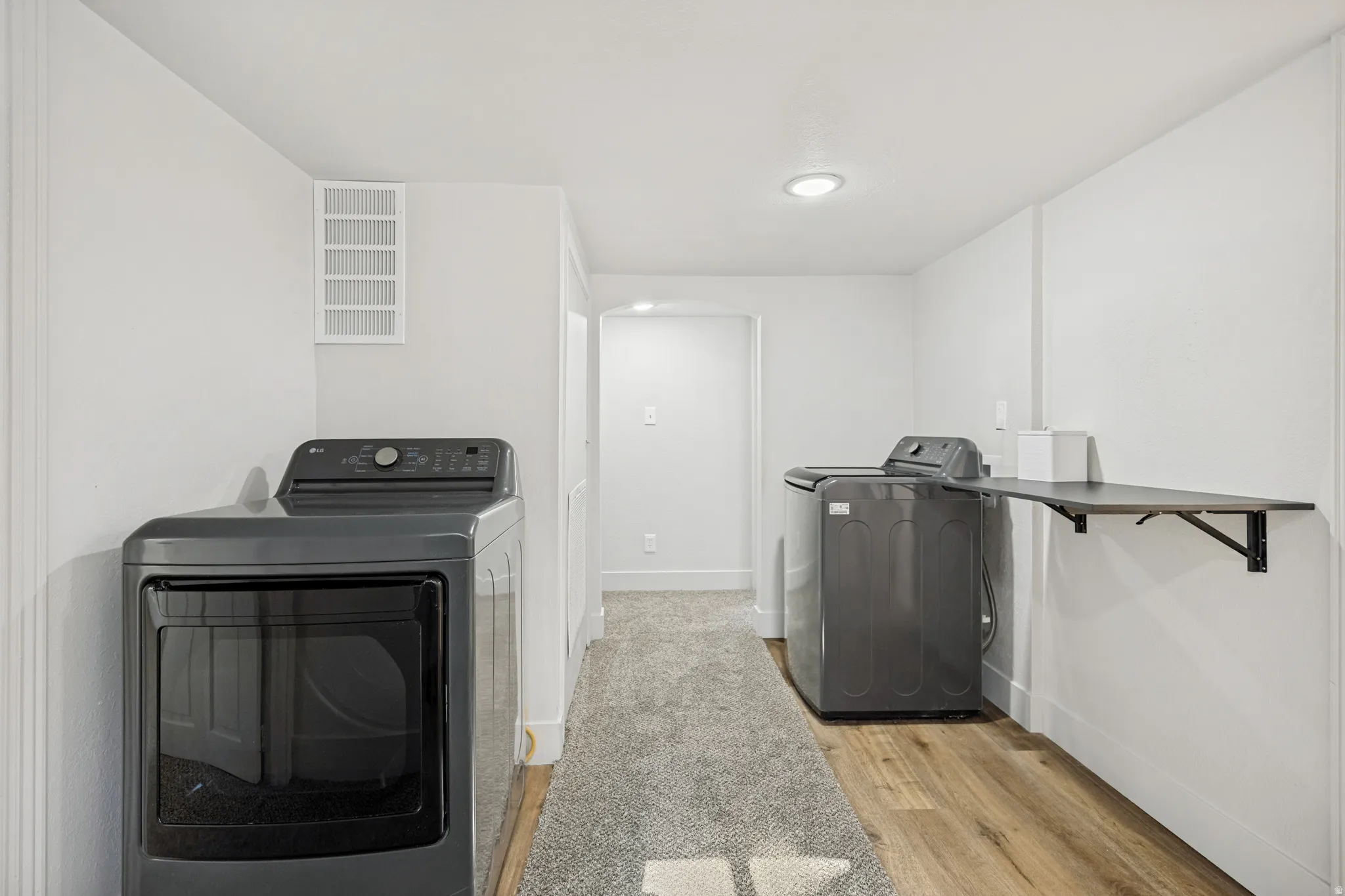 Dedicated laundry area featuring a built-in folding shelf, recessed lighting, wood-finish flooring, and a neutral color palette