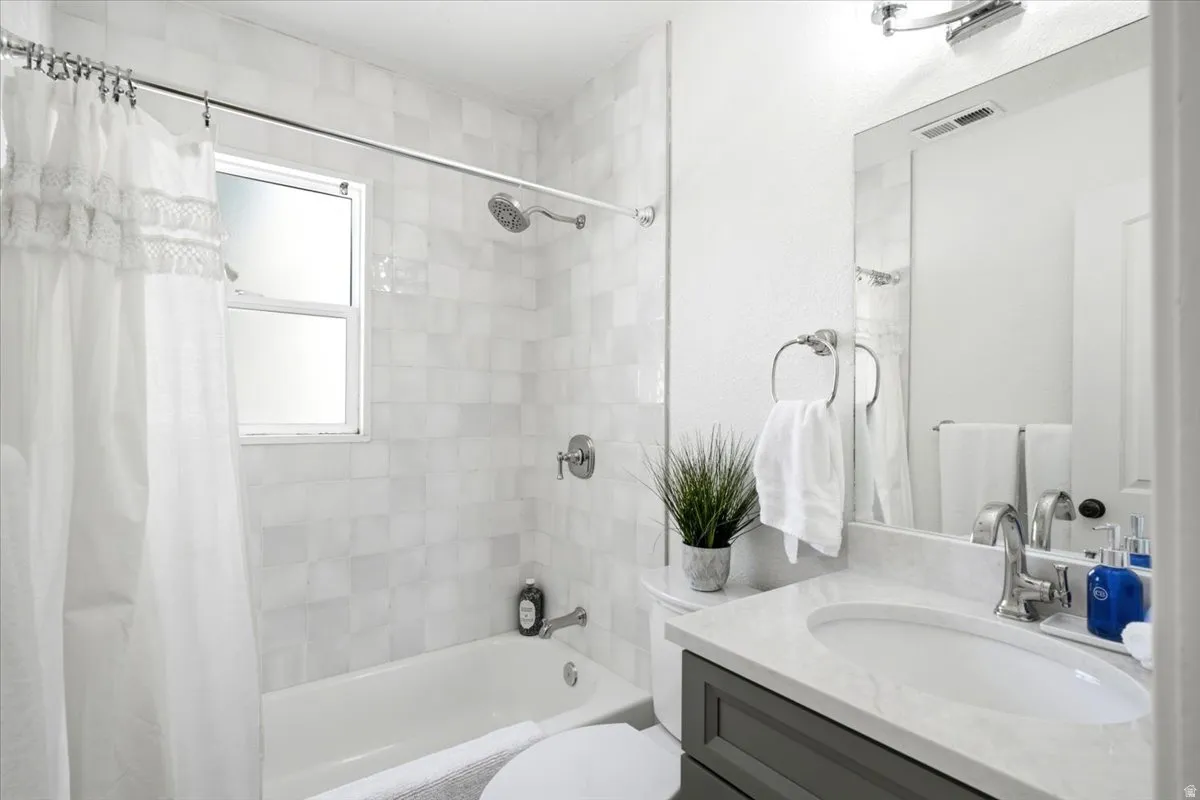 Bathroom featuring a full vanity with a stone countertop, an undermount sink, and a framed mirror