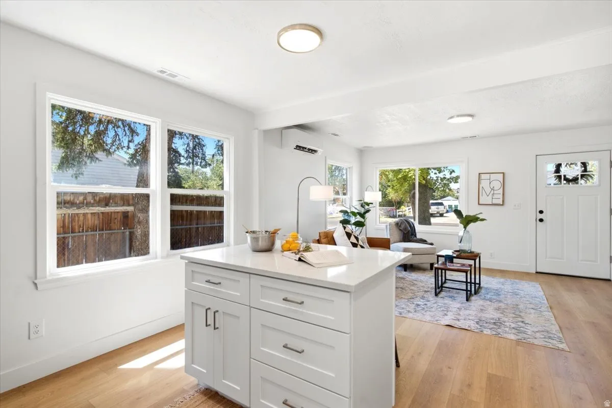 Bright open-concept living space featuring a central island with white cabinetry and a light-toned countertop