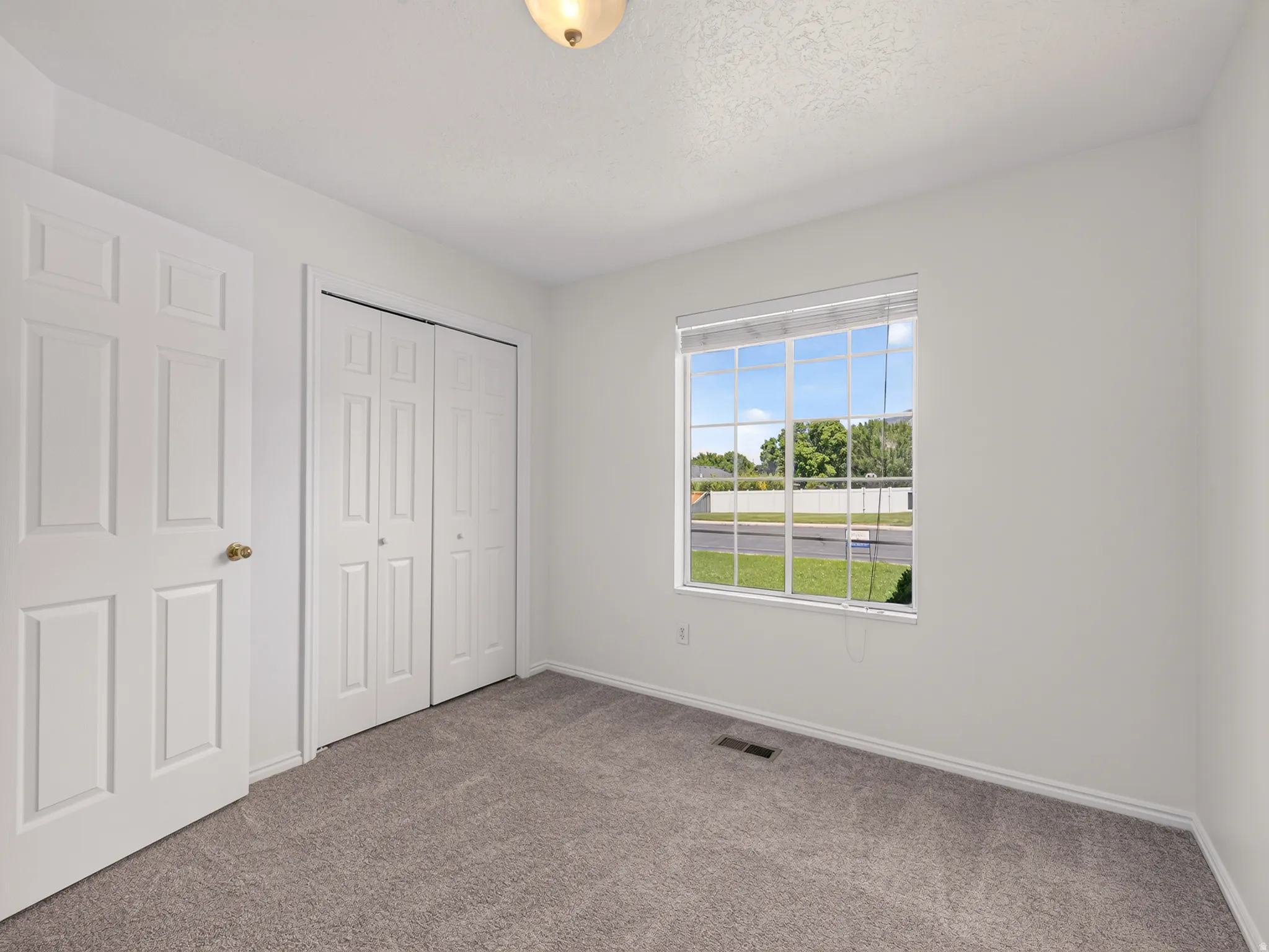 Broad window with blinds, white trim, and a clear exterior view