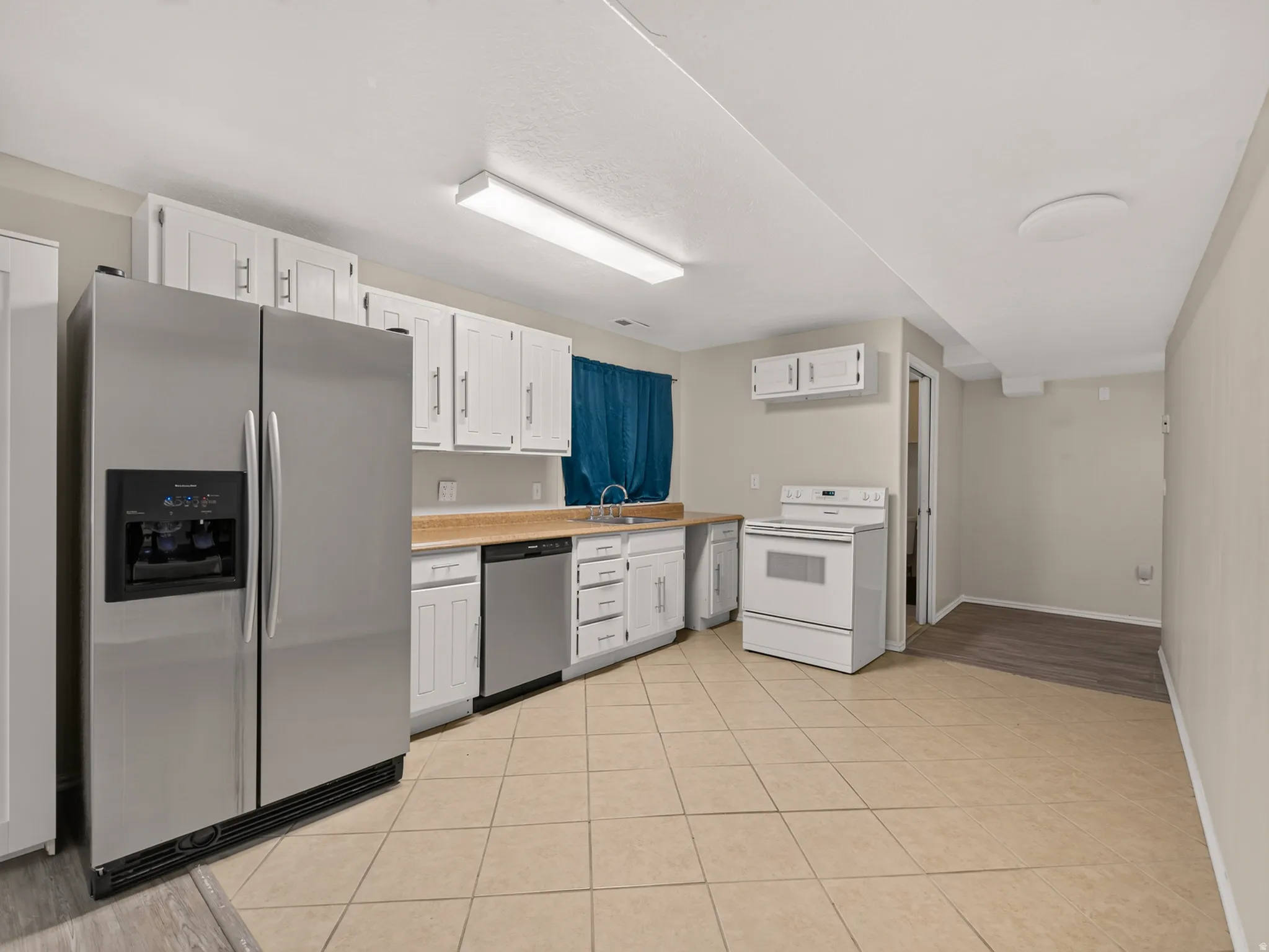 Kitchen featuring white cabinetry, stainless steel refrigerator, and tile flooring