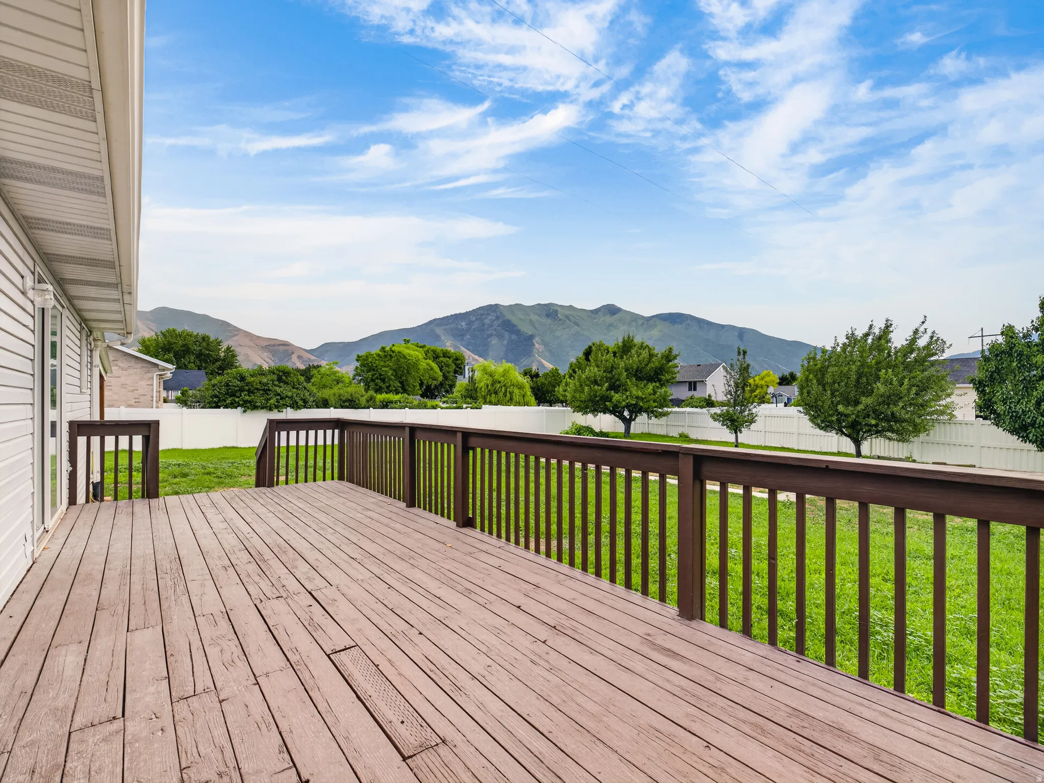 Spacious outdoor deck with dark wood railing and mountain backdrop