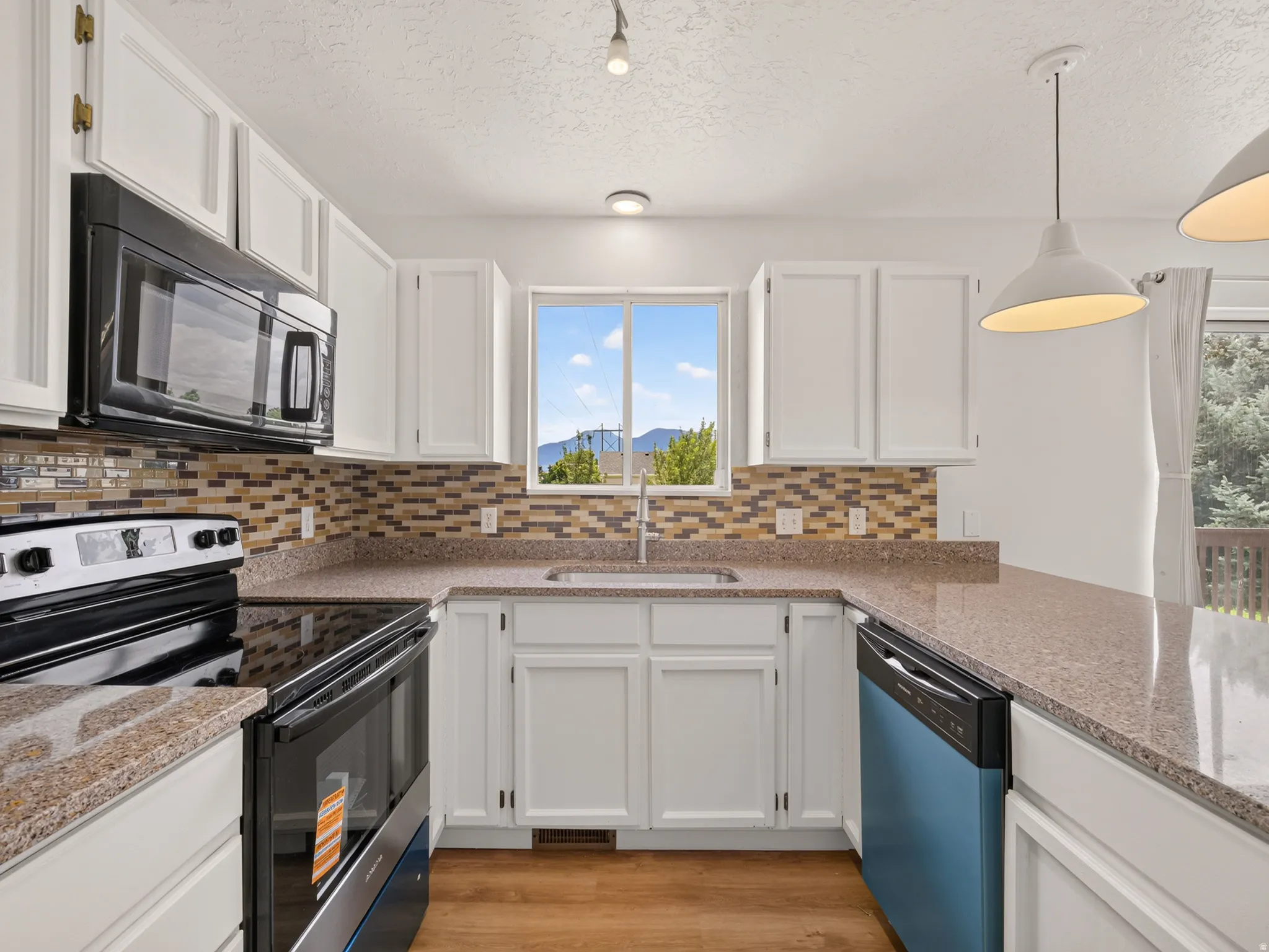 U-shaped kitchen featuring white cabinetry, light-toned countertops, and a mosaic tile backsplash