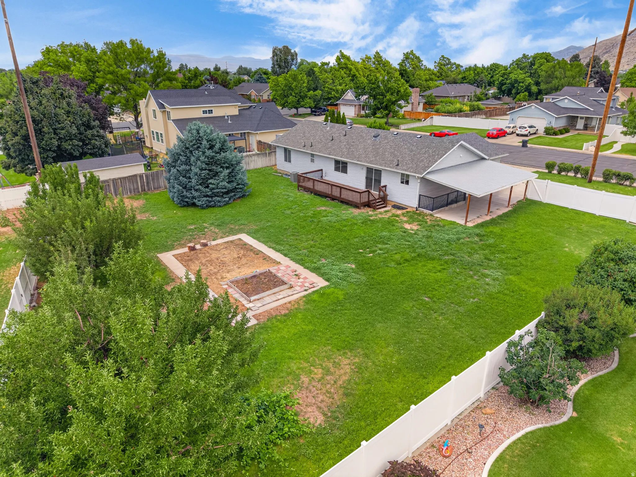 Expansive backyard featuring a manicured lawn, established trees, and a raised garden bed