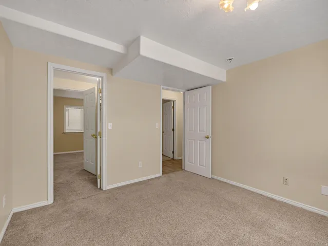 Neutral-toned room featuring light beige walls and textured carpeting