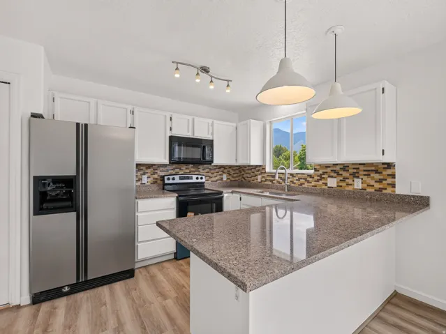 Kitchen featuring white cabinetry, stone-finish countertops, and wood-finish flooring