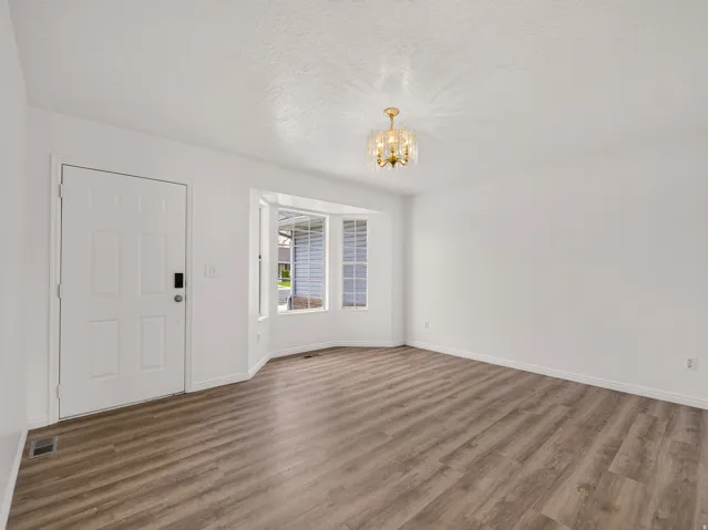 Inviting entry space featuring wood-finish flooring, a contemporary bay window, and a modern gold-tone chandelier