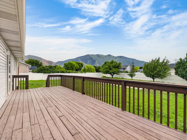 Spacious outdoor deck with dark wood railing and mountain backdrop