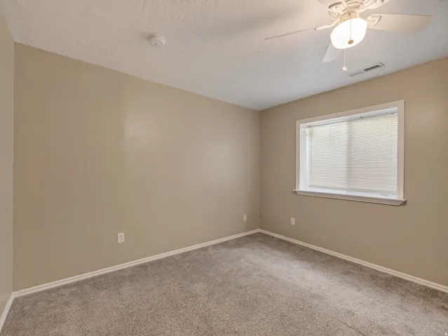 Carpeted room featuring a ceiling fan with integrated lighting, neutral wall paint, white baseboards, and a window with blinds