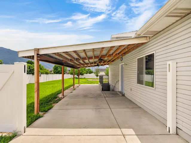 Covered patio area featuring a concrete slab, wood support beams, and a corrugated roof