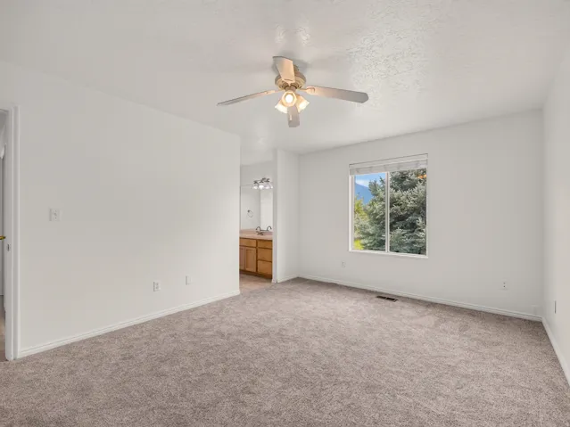 Carpeted room with a ceiling fan light fixture