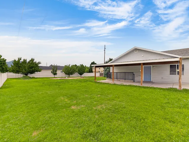 Expansive backyard featuring a large green lawn and a covered patio