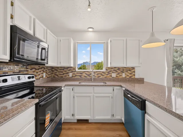 U-shaped kitchen featuring white cabinetry, light-toned countertops, and a mosaic tile backsplash