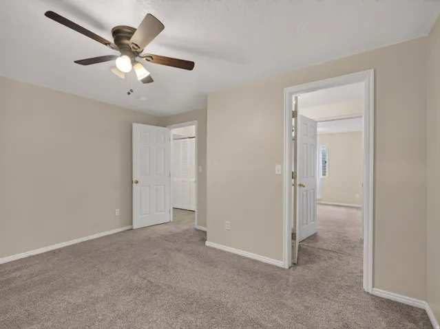 Neutral-toned walls and plush carpeting in this room with a ceiling fan with integrated lighting