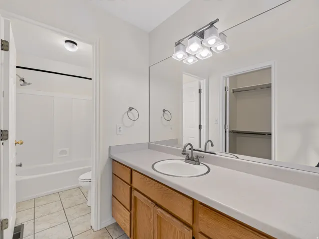 Bathroom featuring a spacious vanity with an integrated sink, a large mirror, and a multi-bulb light fixture