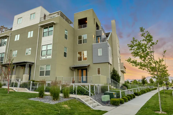 Multi-level modern stucco exterior with multiple balconies and a rooftop deck