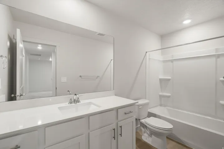 Bathroom featuring a white vanity with an integrated sink, polished chrome faucet, and expansive wall-mounted mirror