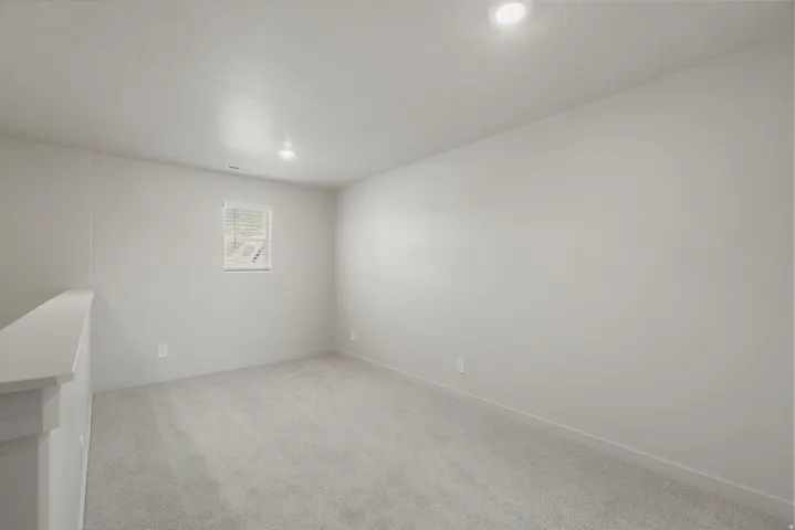 Carpeted room featuring a single window with blinds, recessed ceiling lighting, and light-toned wall finishes