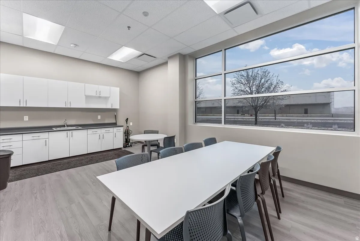 Open-concept room featuring a wall of expansive windows, light wood-finish flooring, and a drop ceiling with integrated lighting