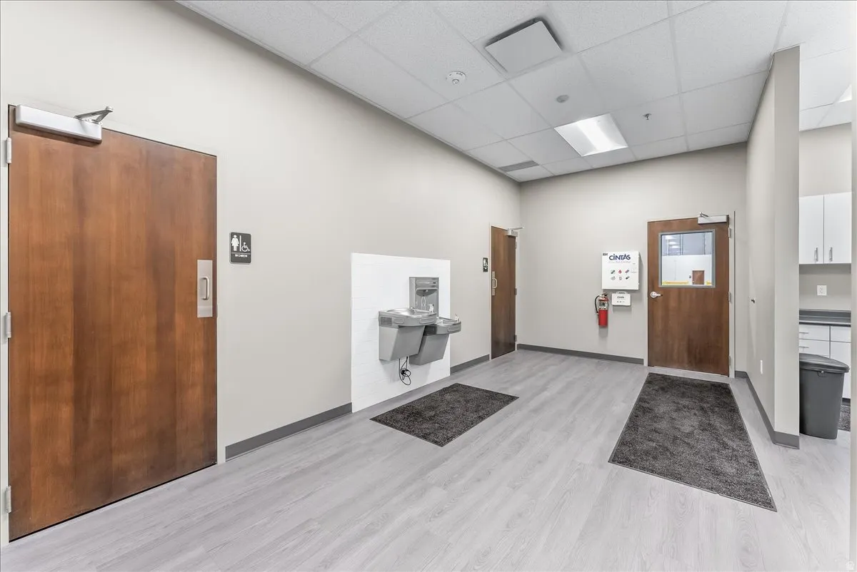 Hallway featuring light wood-finish flooring, light grey walls, and multiple solid wood doors
