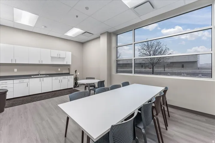 Open-concept room featuring a wall of expansive windows, light wood-finish flooring, and a drop ceiling with integrated lighting
