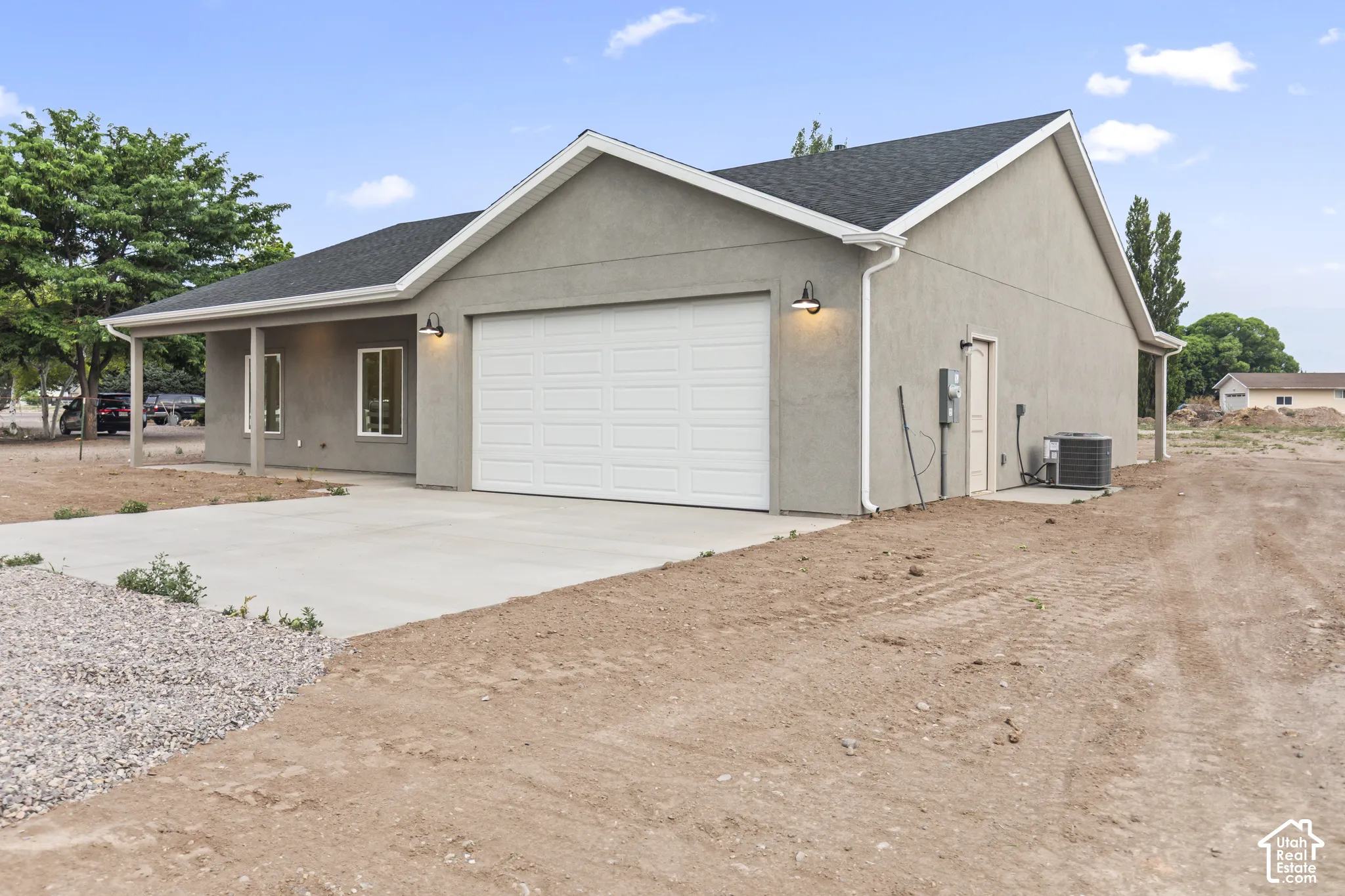 Contemporary stucco exterior with an attached garage, covered front porch, and concrete driveway