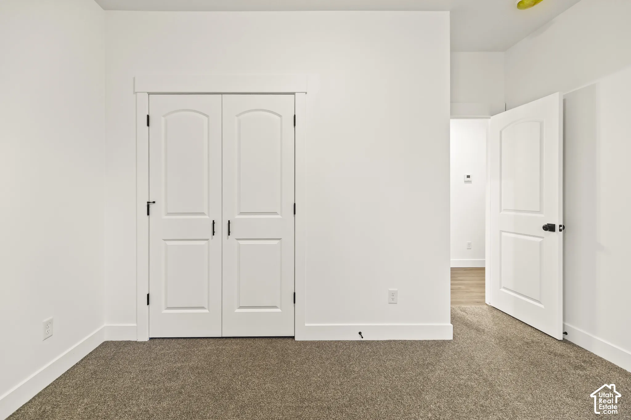 Interior room featuring neutral carpeting, white walls, and white baseboards