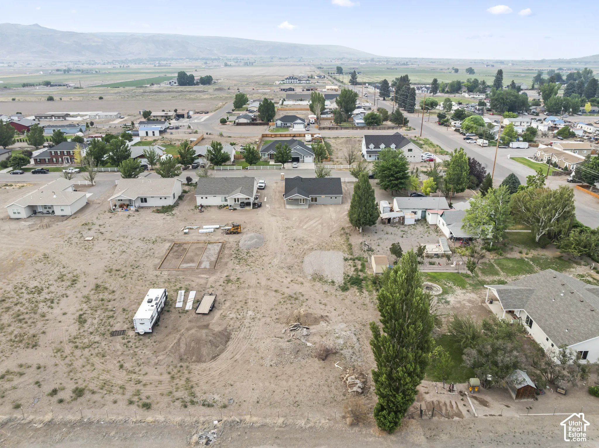 Expansive undeveloped land parcel featuring a level topography, mature trees, and visible building foundations
