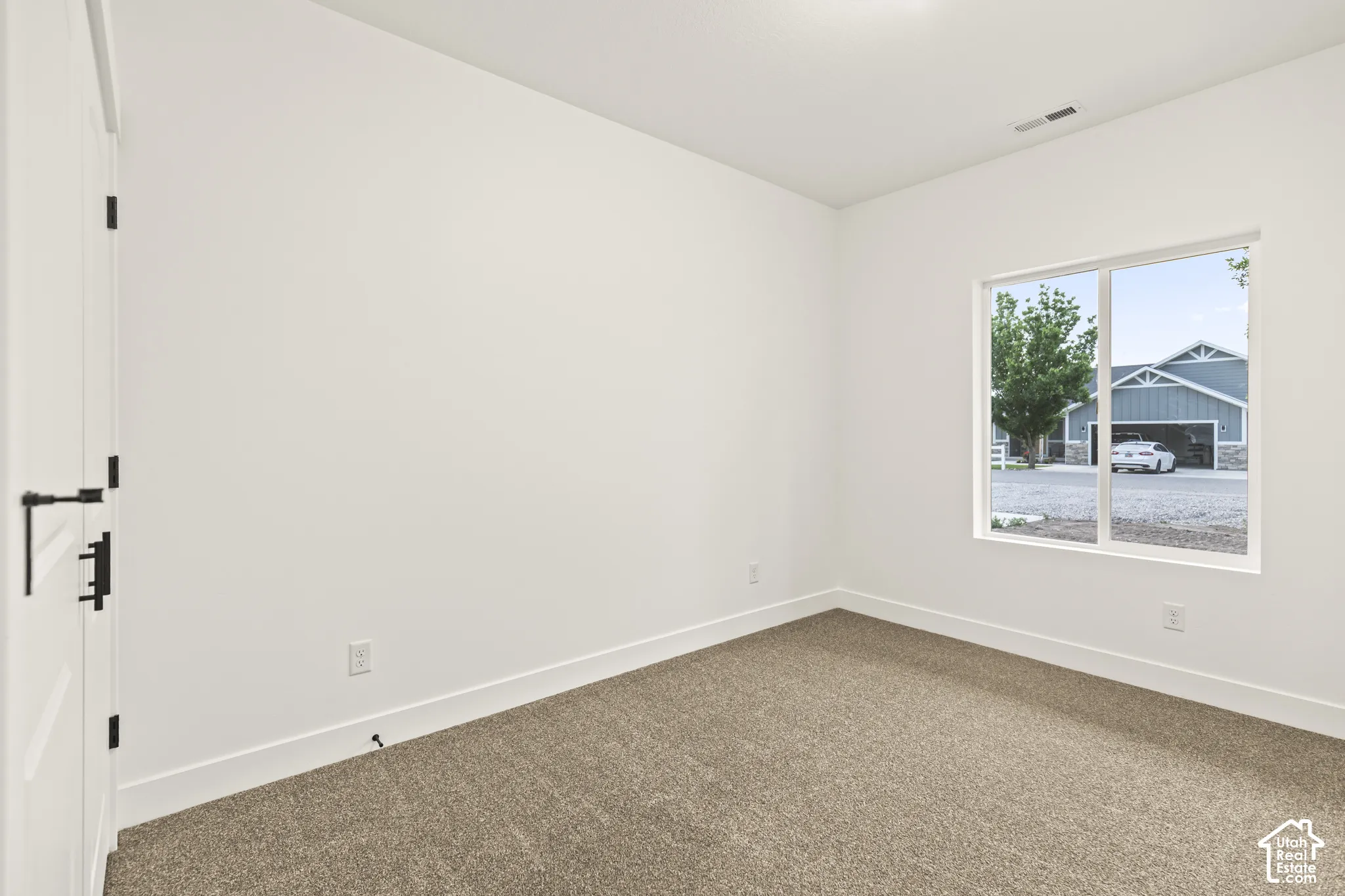 Neutral wall finishes, plush carpeting, bright white baseboards, and a white interior door with black hardware