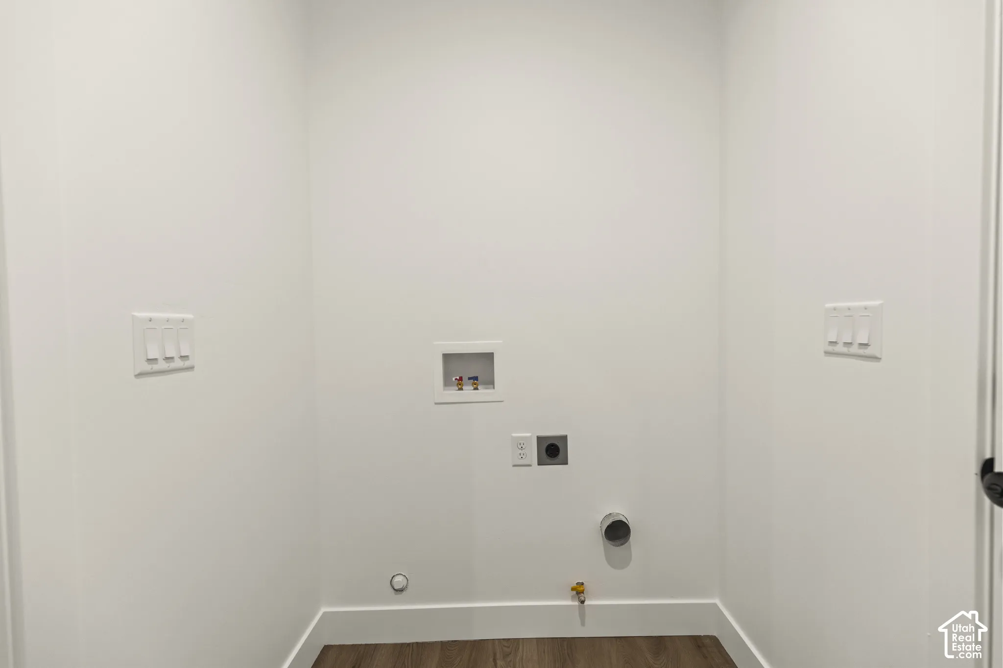 Dedicated laundry area featuring a wood-finish floor and white baseboards