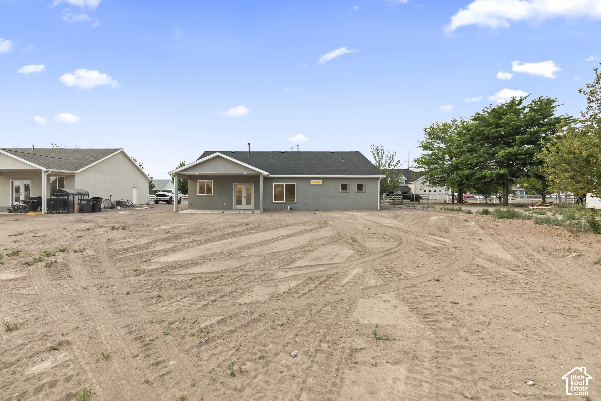 Expansive rear yard with a newly constructed residence featuring a gray exterior finish and multiple windows
