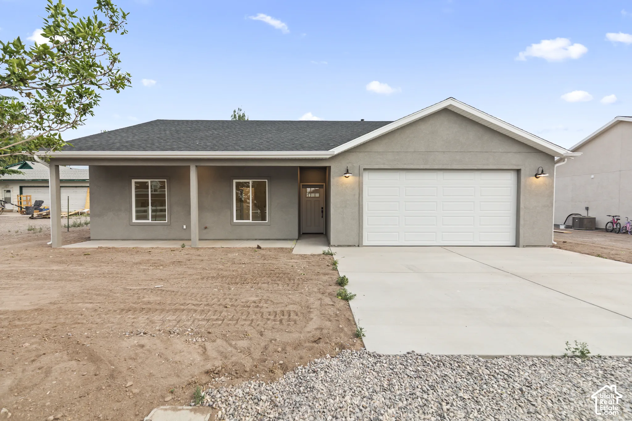 Contemporary single-story residence featuring a stucco exterior, a two-car garage, and a covered porch