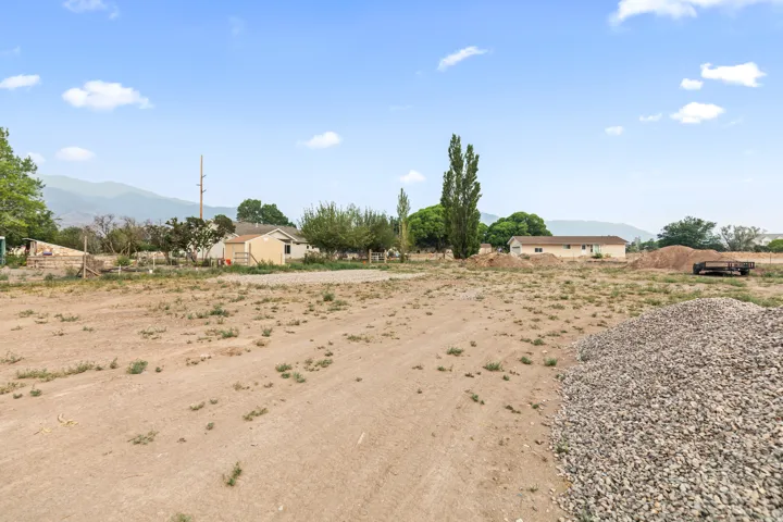 Expansive cleared lot featuring a gravel pile, mountainous background, and a clear blue sky